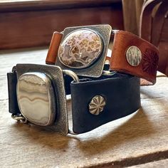 three different colored watches sitting on top of a wooden table