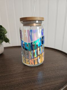 a glass jar sitting on top of a wooden table next to a potted plant