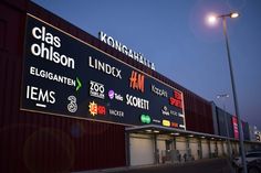 a large sign is lit up in front of a building with many different logos on it