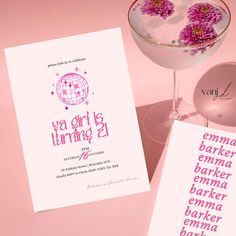 a pink cocktail with purple flowers in it next to a card that says, ya girl is turning 2