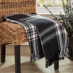 a black and white plaid blanket sitting on top of a chair next to a potted plant