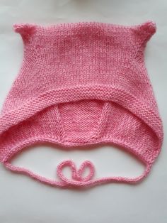 a pink knitted hat with a bow on the side and a string attached to it