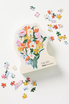 a puzzle box with flowers on it surrounded by pieces of the jigsaw puzzle