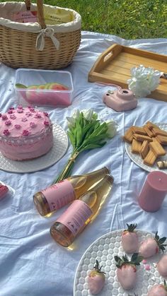 a table topped with cakes and bottles of wine next to other items on top of a white cloth