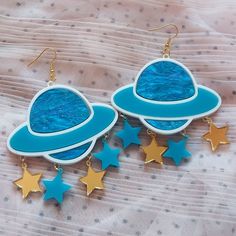 *These out of this world Saturn earrings are made with so many fun and interesting details. *They were laser cut with white, detailed blue, teal, and gold acrylic. *Three star charms are attached under each Saturn piece.   *The pieces were then added to hypoallergenic gold tone earring hooks. **These earrings can be made with sterling silver hooks, regular posts, or wrap around hooks -- if you prefer any of these options just let us know in the notes to seller section during checkout! CONTACT: *Feel free to contact BC with any questions or requests via Etsy conversations or bonescouture [!at] gmail.com SHIPPING: *All packages are wrapped in tissue paper, contain a BC card, and various fun freebies! Receipts are only included if specified. *We are happy to include a personal message for you Blue Celestial Pierced Earrings, Celestial Blue Pierced Earrings, Fun Handmade Blue Jewelry, Blue Themed Earrings For Gift, Themed Blue Earrings For Gifts, Themed Blue Earrings For Gift, Fun Blue Nickel-free Earrings, Blue Fun Dangle Jewelry, Fun Blue Dangle Jewelry