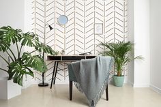 a living room with plants and a desk in the corner, next to a wallpaper