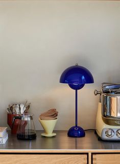 a blue lamp sitting on top of a counter next to a blender and mixer