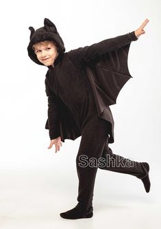 a young boy in a bat costume is posing for the camera with his arms outstretched