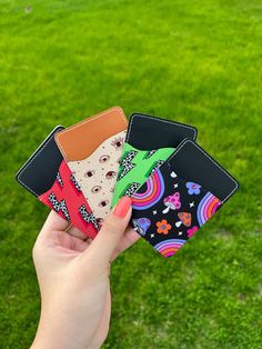 a person holding four different colored wallets in their hand on the green grass field