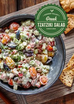 a bowl filled with salad next to crackers