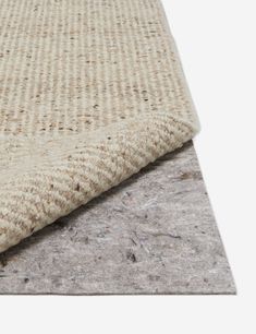 an area rug that has been placed on top of a stone floor with white and beige colors