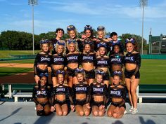 a group of cheerleaders posing for a photo in front of a baseball field