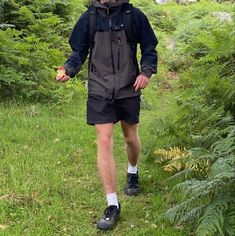 a man walking through the woods with an apple in his hand and wearing hiking gear