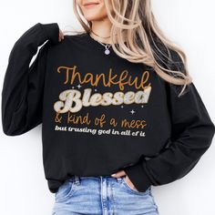 Embrace life's beautiful chaos with our "Thankful, Blessed, and Kind of a Mess, But Trusting God In All Of It" shirt. Perfect for those who know that even in the midst of life's ups and downs, there's always something to be grateful for. Whether you're getting ready for Friendsgiving or just want to share your faith with a touch of humor, this shirt combines comfort and inspiration in one stylish package. Crafted from soft, high-quality 100% ring-spun cotton fabric, this shirt is perfect for eve Inspirational Crew Neck T-shirt For Fall, Inspirational Graphic Print T-shirt For Fall, Inspirational Cotton T-shirt For Fall, Fall Black T-shirt With Lettering, Black T-shirt With Lettering For Fall, Black Lettering T-shirt For Fall, Inspirational Black Pre-shrunk Top, Inspirational Black Cotton Tops, Inspirational Long Sleeve Letter Print T-shirt