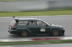 a green car driving down a race track