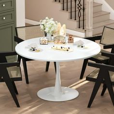 a white table with four chairs around it in front of some stairs and a stair case