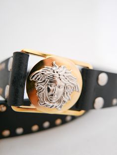 More is more with this never worn 90's Versace studded leather belt. Two tone buckle and large silver Medusa on gold backing framed with small silver Medusa studs. Fits 27.5" - 31.5" with room for additional holes1 1/8" wide Condition: Excellent Designer Silver Belt Buckles With Removable Belt, Designer Black Belt Buckles With Palladium Hardware, Elegant Silver Belt With Metal Logo, Gold Leather Belt Buckle With Metal Logo, Luxury Gold Belt Buckles With Metal Logo, Luxury Silver Belts With Palladium Hardware, Luxury Gold Adjustable Belt Buckle, Luxury Adjustable Gold Belt Buckle, Luxury Adjustable Belt With Buckle