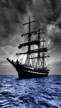 a black and white photo of a ship in the ocean with dark clouds above it