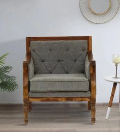 a grey chair sitting next to a table with a white vase on top of it