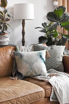 a living room filled with lots of different types of pillows and blankets on top of a couch