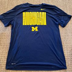 Nike Dri-Fit Michigan Wolverines T-Shirt Size Xl. Nwot. Yellow Sports T-shirt With Logo Print, Yellow Sports T-shirt With Logo, Yellow Pre-shrunk Tops For Fan Merchandise, Nike Blue Fan Apparel Tops, Nike Blue Tops For Fan Merchandise, Yellow College Top For Team Spirit, Yellow Graphic Tee For Sports, Sporty Yellow T-shirt For Fan Merchandise, Casual Yellow T-shirt With Team Name