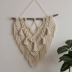 a white wall hanging next to a potted plant