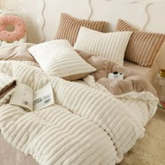 an unmade bed with pillows and blankets on it, next to a donut pillow