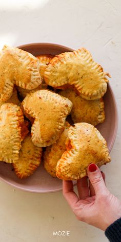 a person holding a plate with several small pastries on it and the other hand reaching for one