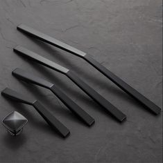 four black knives and spoons on a dark surface with one knife in the middle