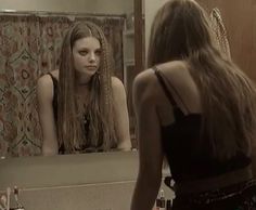 a woman is looking at her reflection in the mirror while she brushes her long hair