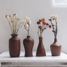 three vases with flowers in them sitting on a table next to a window sill