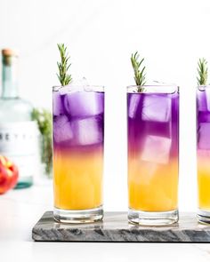 three glasses filled with purple and yellow liquid