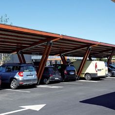 several cars are parked in a parking lot under an awning that is attached to the side of a building