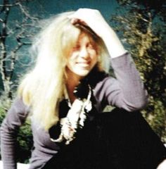 a woman with long blonde hair sitting on a bench