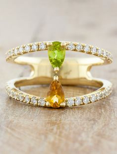 Avie is a captivating split-shank design with two pear shaped gemstones taking center stage, followed by brilliant round cut diamonds sprinkled along the band. A client wanted a custom "just because" gift for his wife featuring their children's birthstones peridot and citrine. She has a unique, sentimental flair, while remaining chic and classic. Setting Only Cost: 14k rose, yellow & white gold $3000 platinum $3500 #kenanddanadesign #birthstone #splitshank #uniqueengagementri Anniversary Peridot Jewelry With Diamond Accents, Wedding Jewelry With Yellow Sapphire And Gemstone Accents, Wedding Jewelry With Peridot Gemstone Accents, Peridot Gemstone Wedding Jewelry, Fine Jewelry Pear-shaped Multi-stone, Pear-shaped Diamond Jewelry With Accent Stones, Unique Pear Shaped Jewelry For Anniversary, Teardrop Peridot Jewelry For Anniversary, Fine Jewelry Pear-shaped Promise Jewelry