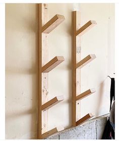 two wooden bookshelves sitting on top of a wall next to a coat rack