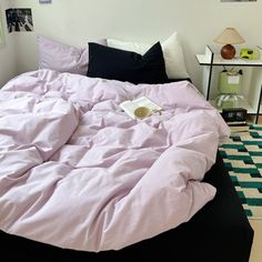 an unmade bed with pink sheets and black pillows