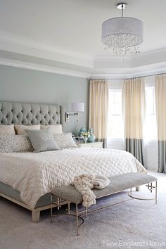 a bedroom with gray walls and white bedding in the center, along with a chandelier hanging from the ceiling