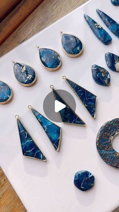 a table topped with lots of different types of blue stone earrings on top of a white surface