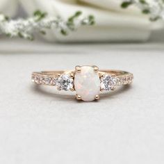 a white opal and diamond ring sitting on top of a table