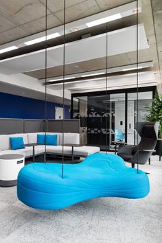 an office with blue and white furniture in the middle of it, hanging from glass walls