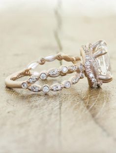 two wedding rings with diamonds on them sitting on top of a stone slabd floor