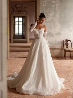 a woman in a white wedding dress is looking down at the floor with her hand on her head