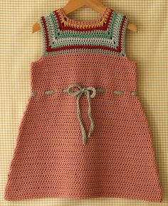 a crocheted dress hanging on a wooden hanger