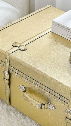 a yellow suitcase sitting on top of a white fluffy rug next to a book and pen