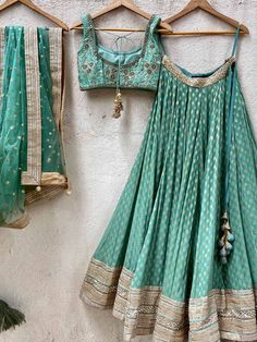 A three-piece jade green zari lehenga set from the Priti Sahni collection. This beautiful georgette small butti green lehenga with a heavy border of sequin, pearl and zari work detail with green accent is paired with a raw silk green blouse with sequin and zardosi embroidery detail all over. The lehenga has side hanging ball tassels to the waistline. And the blouse has a sequins tassel tie-up at the back. This outfit is completed with a sequin tulle dupatta with jade green accent in net material Green Georgette Lehenga With Cutdana, Green Georgette Lehenga With Cutdana Details, Bollywood Style Green Chinon Choli, Bollywood Green Chinon Choli, Green Chinon Lehenga For Navratri, Green Chinon Lehenga For Reception, Navratri Green Chinon Lehenga, Green Bollywood Choli In Chinon, Designer Green Chinon Choli