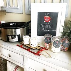 a crock pot and coffee mugs are sitting on a table next to a sign