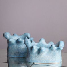 two blue vases sitting next to each other on top of a glass countertop