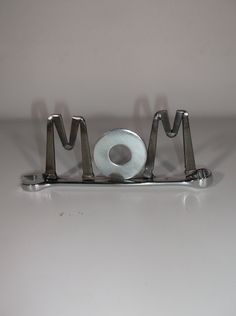 a metal object with the word mom spelled out in it's center, sitting on a white surface