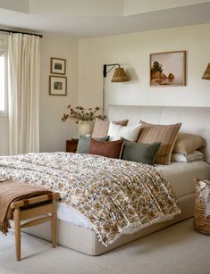 a bedroom with a large bed sitting next to a window filled with curtains and pillows